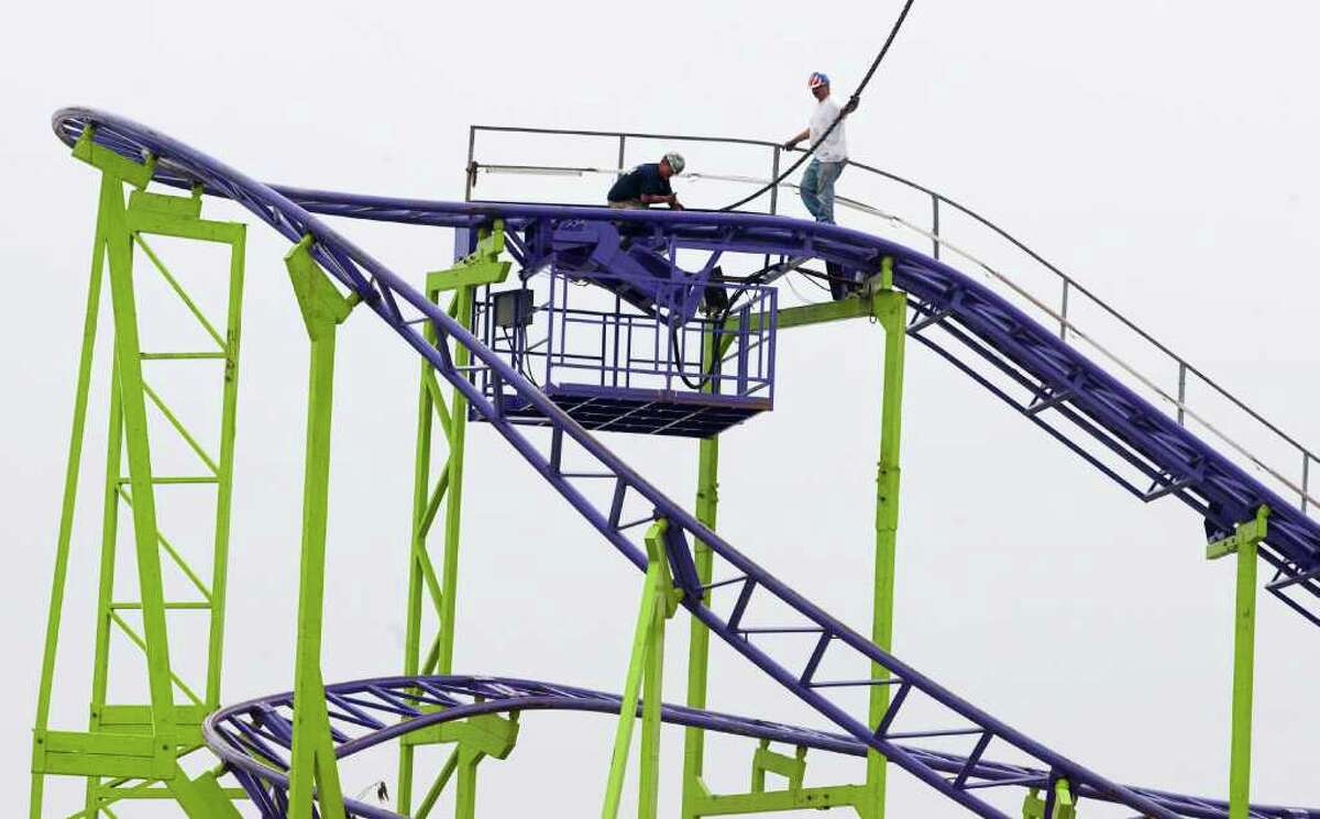 James Murray, left, and Robert Hall work on installing the Dstorm roller coaster at the carnival for RodeoHouston at Reliant Park. This ride is not the same as the one from which a rider plunged to his death last year.