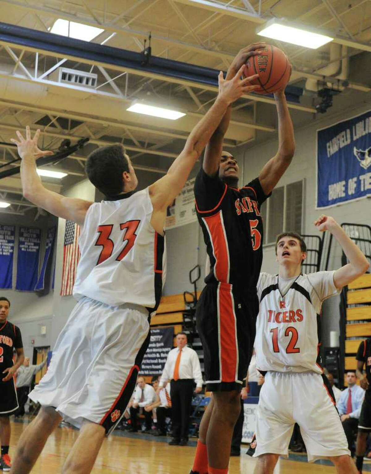 Stamford's Shawn Padilla goes up for a shot as Ridgefield's Jack Heller blocks him as Stamford High School and Ridgefield High face off in the FCIAC boys basketball semifinals at Ludlowe High School in Fairfield, Conn., February 25, 2012. Ridgefield won the game 50-46.