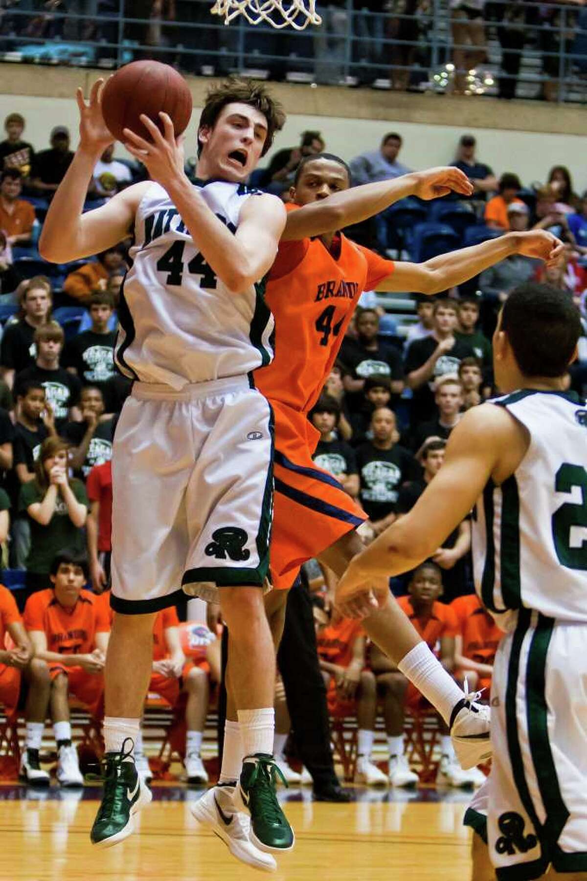 Reagan’s D.J. MacLeay (left) beats Brandeis’s Eric Robinson for a rebound in their Class 5A second-round playoff game Feb. 23 at the UTSA Convocation Center. Brandeis advanced with a 52-43 win.