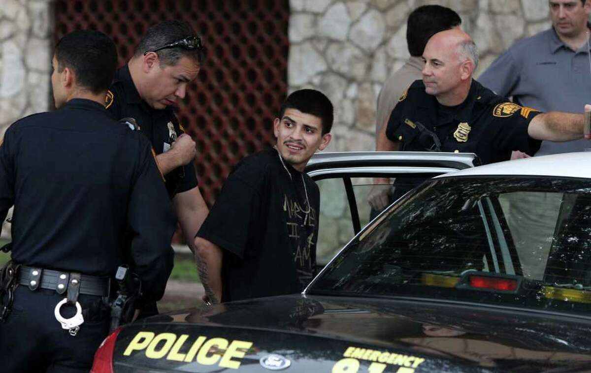 San Antonio Police detain a suspect identified as Eric Daniel Alcoser (center) Wednesday morning, Feb. 29, 2012, at a parking garage at Bowie and Commerce streets after shots were allegedly fired by the suspect after his car rolled over an embankment near the La Quinta Inn at Interstate 37 and Commerce Street. Alcoser, 19, is charged with deadly conduct and possession of crack cocaine.