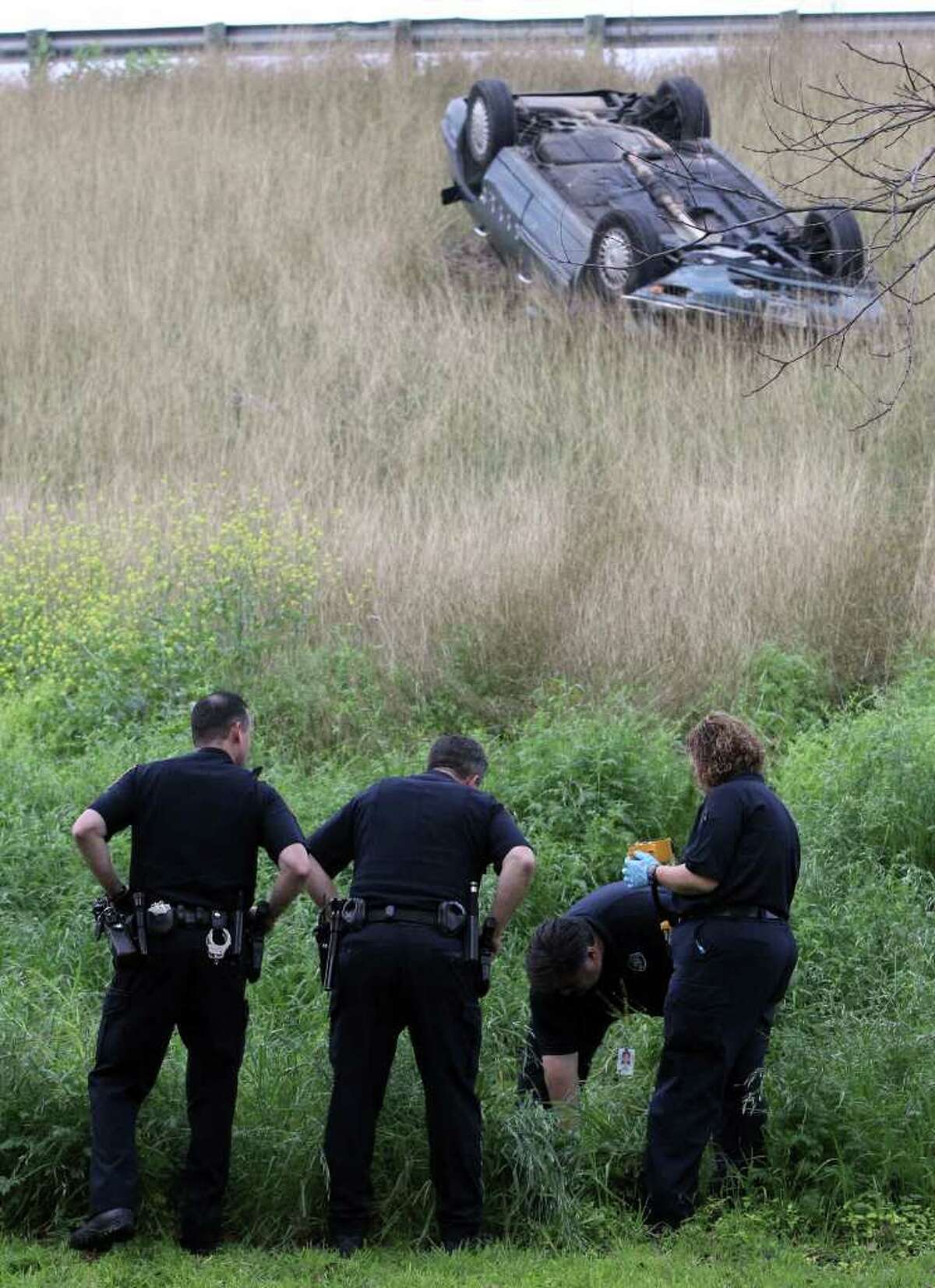 Officers work a rollover scene off Interstate 37 near the Commerce Street exit. Police said the driver shot at a group of people who stopped to see if he was injured, adding that he admitted he fled because he had crack cocaine in his pocket.