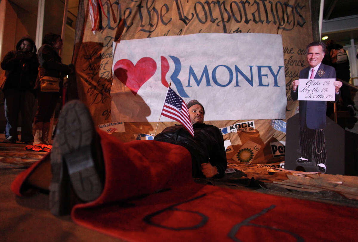 Protester George Karpinski lays under a red carpet laid out by protesters for Mitt Romeny outside of Meydenbauer Center in Bellevue on Thursday, March 1, 2012. The U.S. presidential candidate was hosting an exclusive campaign fundraiser at the convention center in Bellevue.