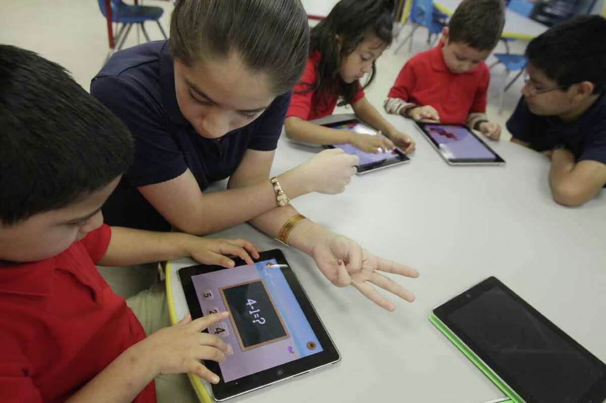 Julian Guevara Lopez, 5, gets help from student volunteer Esmeralda Vega, 12, during their iPad exercises at Rusk Elementary School on Thursday, Feb. 16, 2012, in Houston. Technology is changing the way students learn in the classroom at Rusk Elementary School, HISD science and technology magnet school, where approximately 70 iPads are available to be used for educational purposes. ( Mayra Beltran / Houston Chronicle )