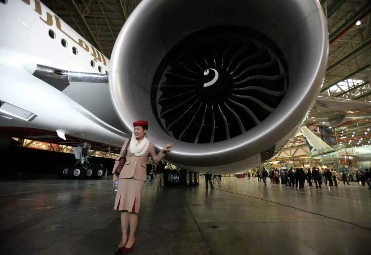 Emirates flight attendant Naoko Fukuda poses next to the engine of Boeing's 1,000th 777 during a ceremony marking the completion of the 1,000th 777 at the assembly plant in Everett on Friday, March 2, 2012.