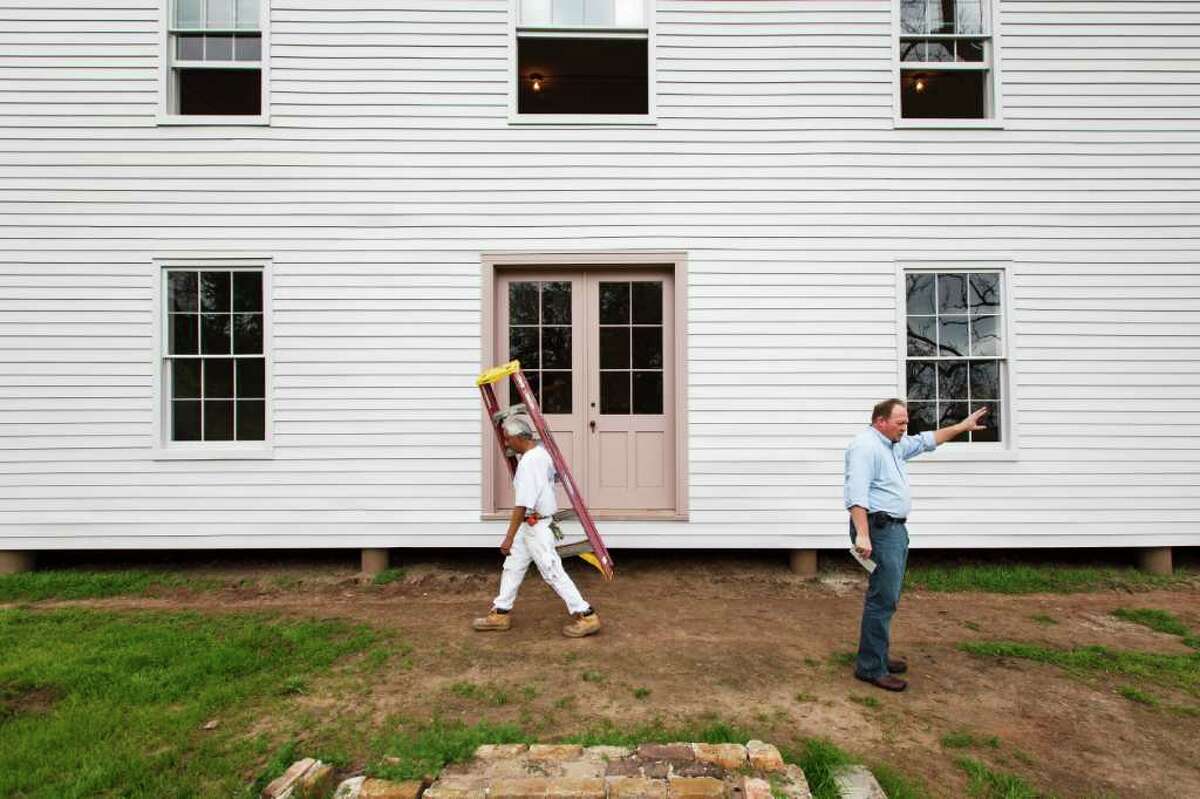 Under the direction of site manager Bryan McAuley, right, workers like Marcos Bailon, carrying ladder, kept busy this week putting final touches on the two-story Greek Revival-style main house at the Levi Jordan Plantation State Historic Site in Brazoria.