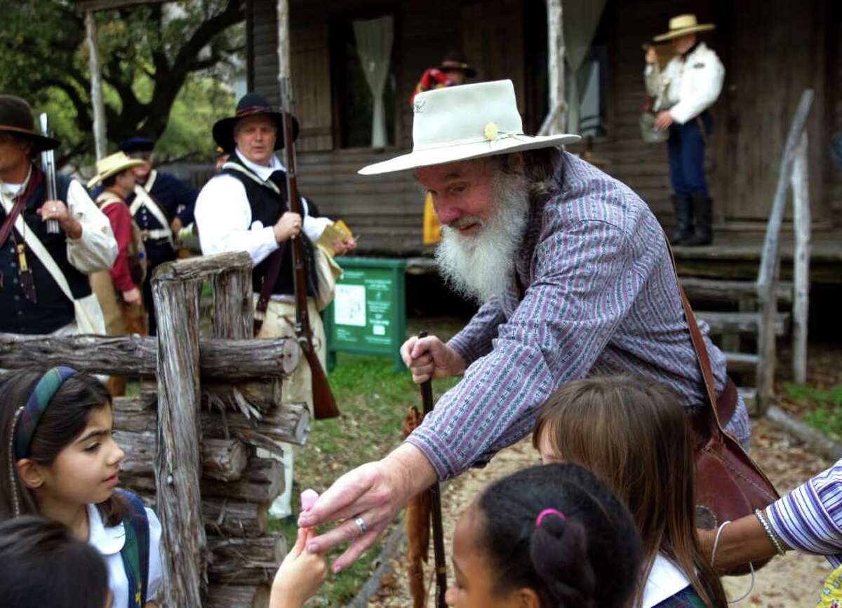 John Lightfoot, of the Texas Army, hands out paper flowers to schoolchildren outside the 1823 Old Place cabin at Sam Houston Park Friday, March 2, 2012, in Houston. The Texas Army commemorated Texas Independence Day Friday. The Texas Army is dedicated to the purposes of perpetuating the memory of those early Texas patriots who worked and fought as the first army of the Republic of Texas.