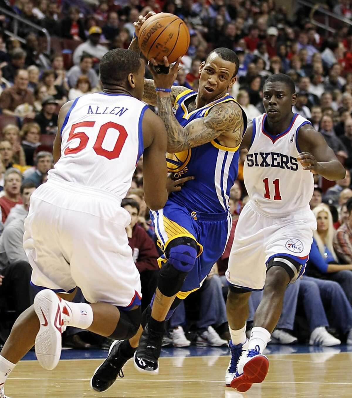 Philadelphia 76ers forward Lavoy Allen (50) and guard Jrue Holiday (11) pressure Golden State Warriors guard Monta Ellis (8) in the first half of an NBA basketball game, Friday, March 2, 2012, in Philadelphia.
