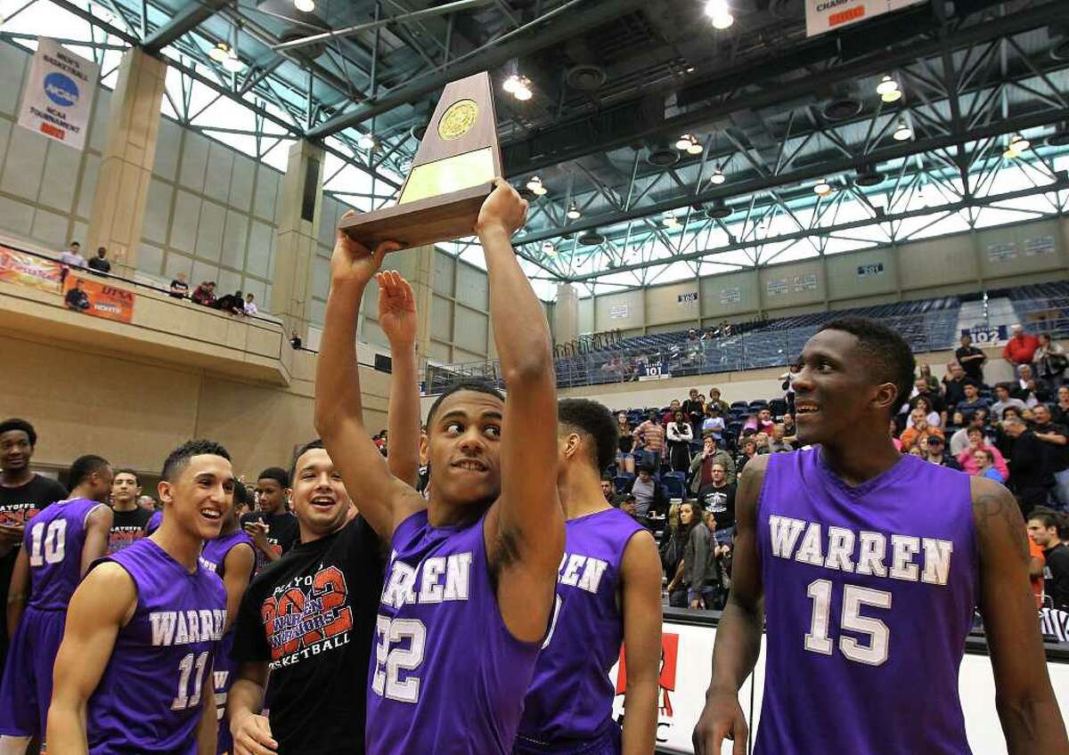 Warren's Jordan Corona (22) holds up the Region IV-5A trophy as teammates look on after the Warriors defeated the Clark Cougars in the Region IV-5A boys basketball finals at UTSA on Saturday, Mar. 3, 2012. Warren defeated Clark, 65-56, to earn a trip to the state tournament.