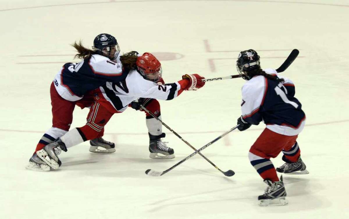 New Canaan's Olivia Hompe (22) takes a shot as West Hartford's Juliana Bailey-Simao (10) and Racheal Aronow (17) defend during the Connecticut High School Girls' Hockey Association Championship Game at Ingalls Rink in New Haven on Saturday, Mar. 3, 2012.