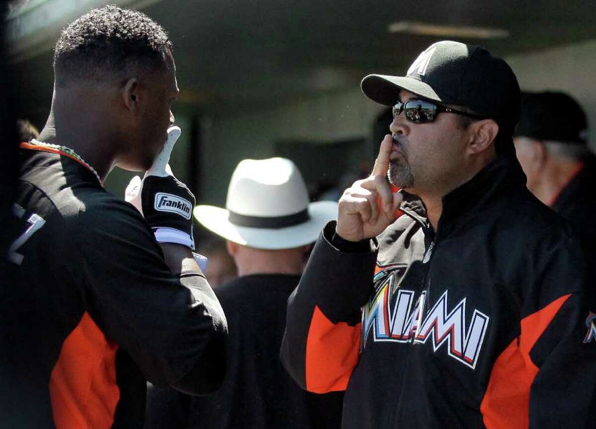 Miami Marlins manager Ozzie Guillen, right, and third baseman Hanley Ramirez make a sign to each other in the dugout before the start of a spring training baseball game against the St. Louis Cardinals, Monday, March 5, 2012, in Jupiter, Fla.