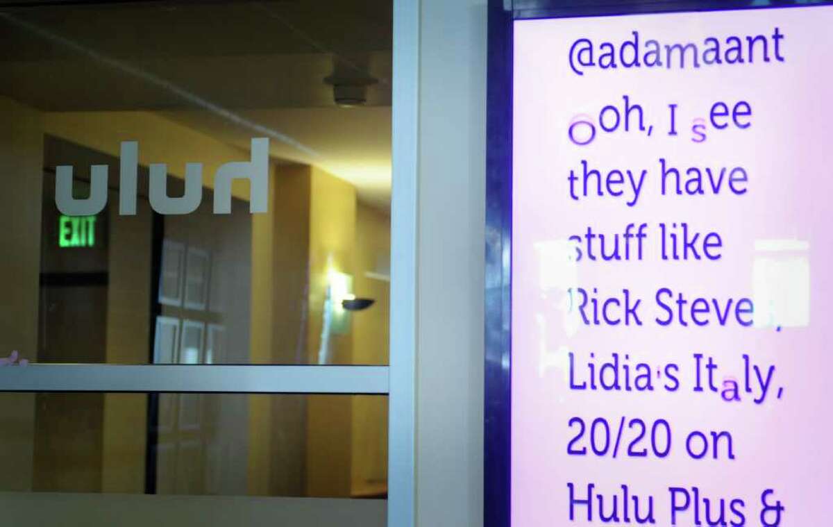 A screen shows live updates of tweets from users who mention Hulu inside their Seattle office.