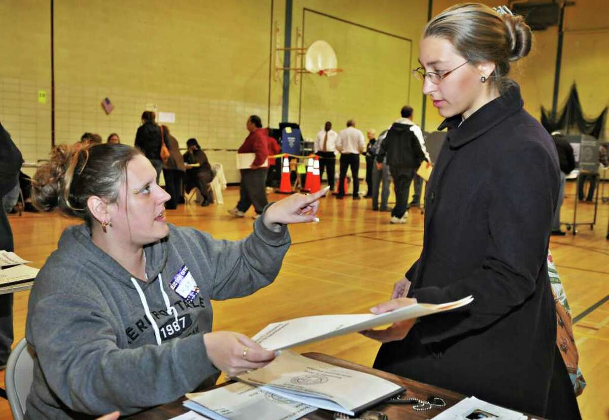 Election inspector Katherine Taylor, left, gives a ballot and some instructions to Brittney Belz before she votes at Schenectady High School Tuesday November 2, 2010. (John Carl D'Annibale / Times Union)