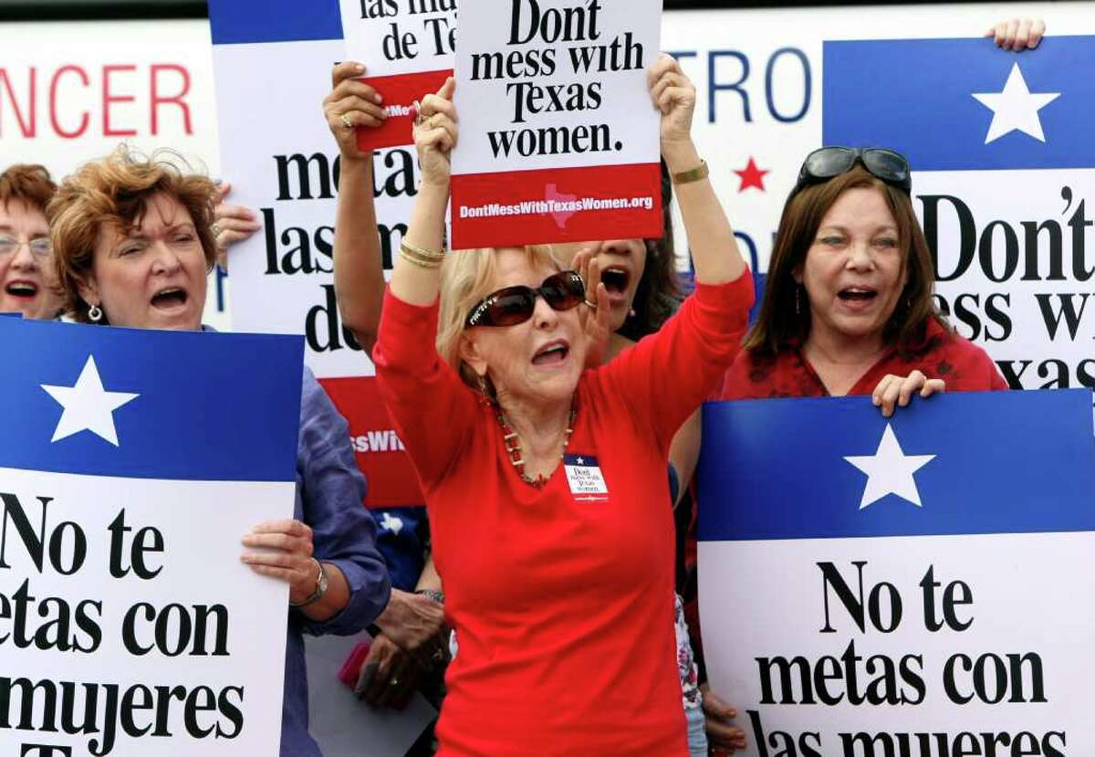 Mary Green, Peg Armstrong and Jan Perrault hold up signs during Women's Health Express, a bus event held to protest the attempt to cut Planned Parenthood out of Women's Health Plan in San Antonio, Texas on Tuesday, March 6, 2012.