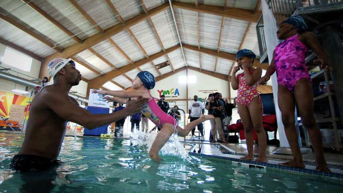 Cullen Jones, an Olympic gold medalist, left catches Helena Carnot, 5, during a swimming class he's instructing for the Make a Splash program, Wednesday, March 7, 2012, at the Clay Road Family YMCA in Houston. Make a Splash is a national child focused safety initiative, with the help of ConocoPhillips, reaching 1.1 million people since it's inception teaching water safety in 47 states.