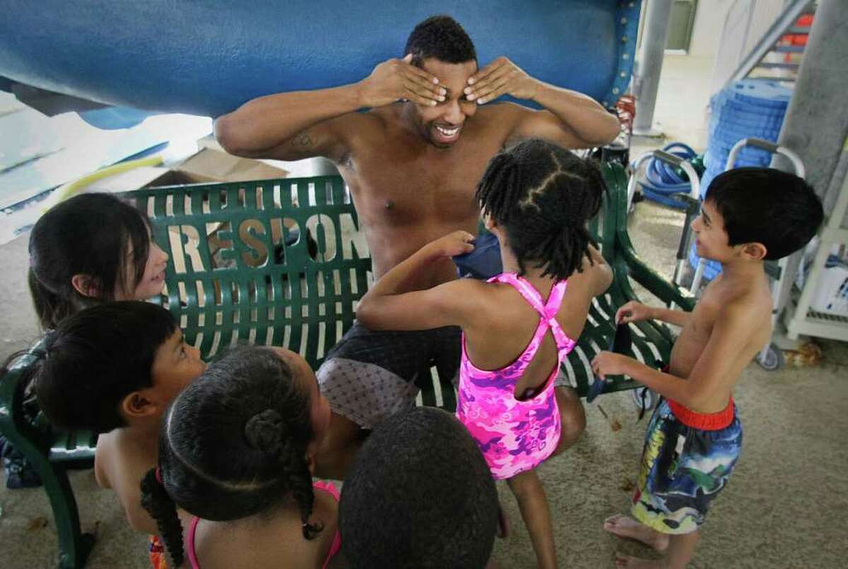 Cullen Jones, an Olympic gold medalist, facing, shows pre kindergarten students how to put on a swim cap before he instructs a swimming class for the Make a Splash program, Wednesday, March 7, 2012, at the Clay Road Family YMCA in Houston. Make a Splash is a national child focused safety initiative, with the help of ConocoPhillips, reaching 1.1 million people since it's inception teaching water safety in 47 states.