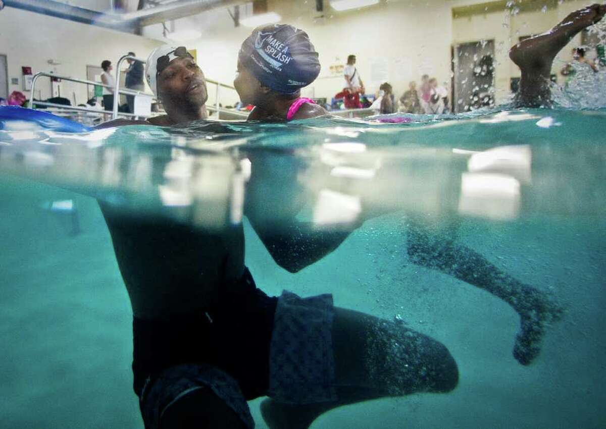Cullen Jones, an Olympics gold medalist, helps Aralyn Fontenet, 5, use a kick board during a swimming class he's instructing for the Make a Splash program, Wednesday, March 7, 2012, at the Clay Road Family YMCA in Houston. Make a Splash is a national child focused safety initiative, with the help of ConocoPhillips, reaching 1.1 million people since it's inception teaching water safety in 47 states.