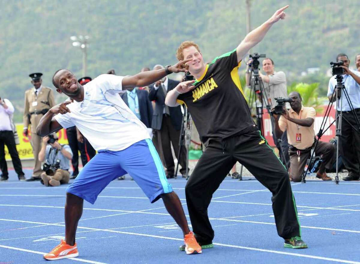 Britain's Prince Harry and Usain Bolt, Jamaica's champion do the lightening strike pose, on the track at the University of the West Indies in Kingston, Jamaica on March 6, 2012. Prince Harry gave Bolt a run for his money Tuesday. Minutes after teaching the prince the basics of starting, Bolt was surprised to see his royal competitor race 50 meters down the track, in what would be described internationally as a false start. AFP PHOTO/Anthony FOSTER