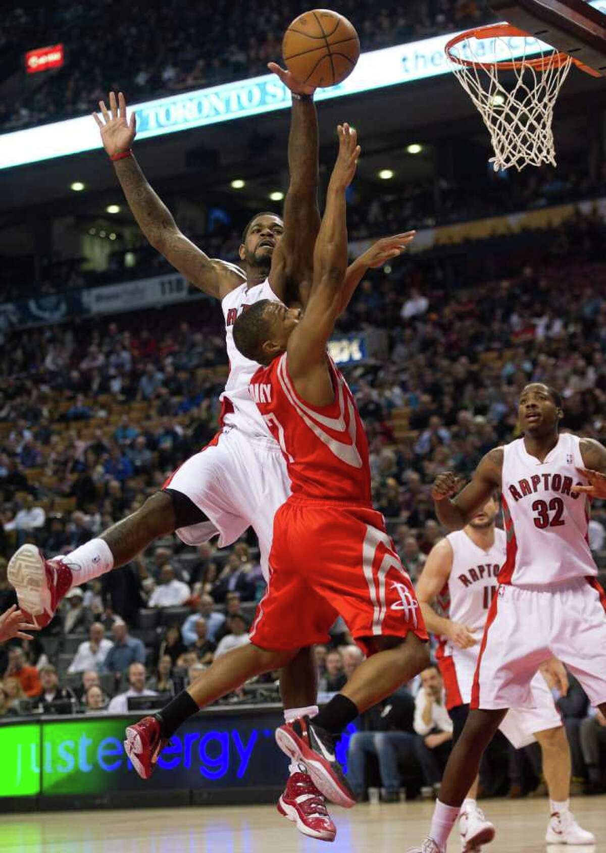 Toronto Raptors forward Amir Johnson, left, and Houston Rockets guard Kyle Lowry, center, reach for the ball during the first half of an NBA basketball game in Toronto on Wednesday, March 7, 2012. (AP Photo/The Canadian Press, Nathan Denette)