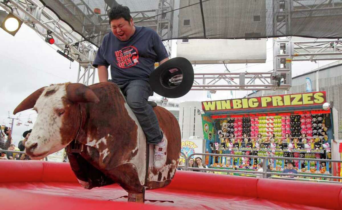 Japanese Sumo wrestler Takuji Noro who competes as "Noro" rides a mechanical bull during a tour of The Houston Livestock Show & Rodeo Wednesday, March 7, 2012, in Houston.