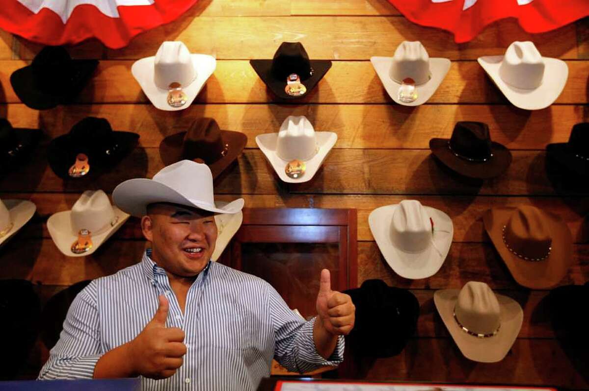 Sumo wrestler Byamba Ulambayar, gives a thumbs up after being fitted with a cowboy hat at Pinto Ranch Fine Western Wear Wednesday, March 7, 2012, in Houston. Four world champion wrestlers including Yamamotoyama Ryuichi Keisuke Kamikawa, Takuji Noro and Byamba Ulambayar are in town for a presentation during the Third Annual Men of Menil black-tie event titled the Art of Sumo tomorrow at the Menil.