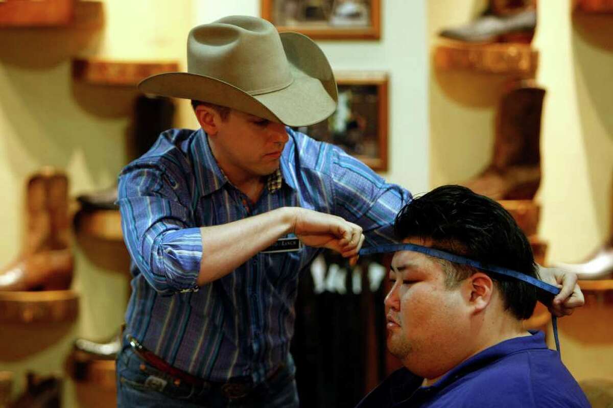 Sumo wrestler Yamamotoyama Ryuichi has his head measured by Brian Pansky as a group of sumo wrestlers were fitted with western wear at Pinto Ranch Fine Western Wear Wednesday, March 7, 2012, in Houston.