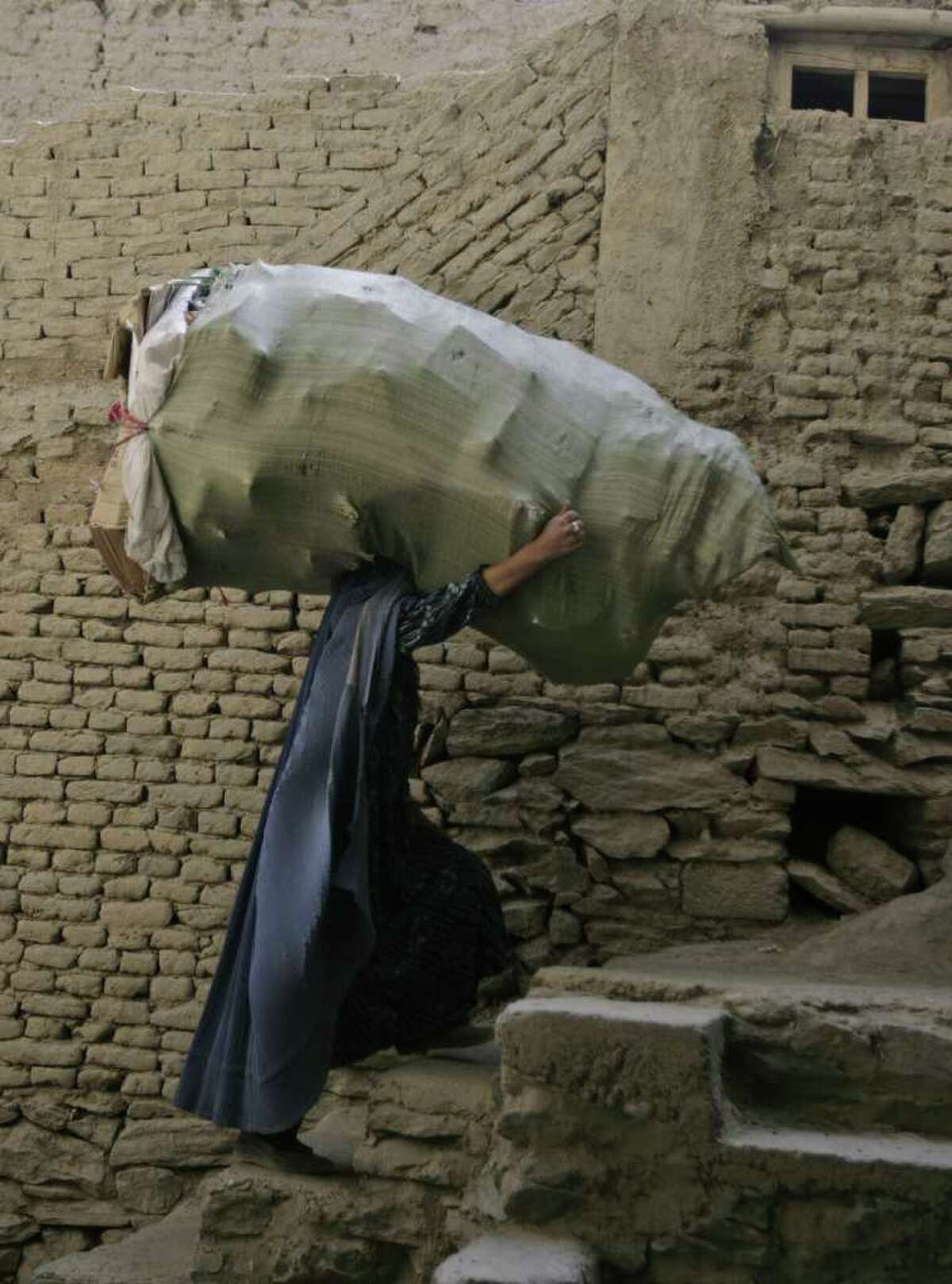 FILE- In this June 14, 2011 picture, an Afghan woman carries goods up the stairs in the old town of Kabul, Afghanistan. Afghanistan's President Karzai endorsed Tuesday March 6 2012 guidelines for women's conduct from the country's clerics' council that activists say represent a giant step backward for women's rights in Afghanistan. (AP Photo/Ahmad Jamshid, File)