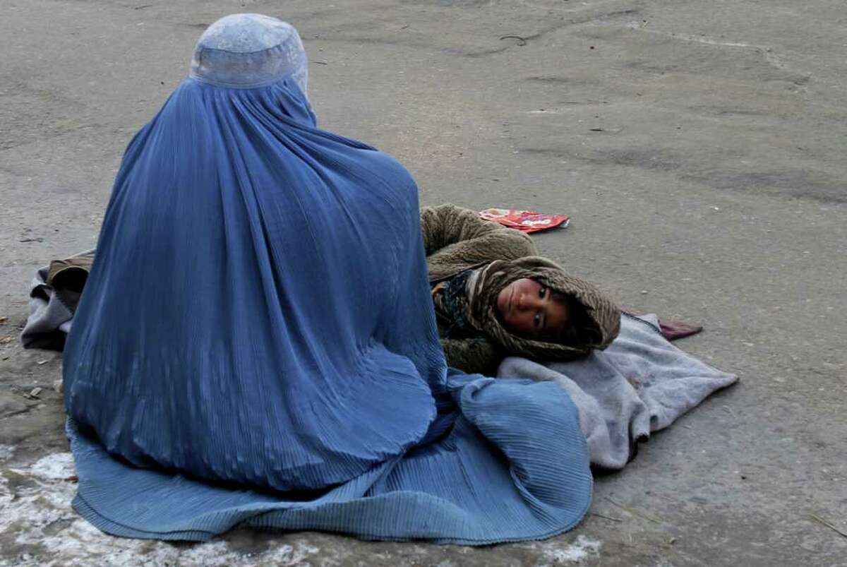 FILE - In this Jan. 25, 2012 file photo, an Afghan woman begs with her child in Kabul, Afghanistan. Afghanistan's president Hamid Karzai on Tuesday, March 6, 2012 endorsed a "code of conduct" issued by an influential council of clerics that activists say represents a giant step backward for women's rights in the country. (AP Photo/Ahmad Jamshid, File)