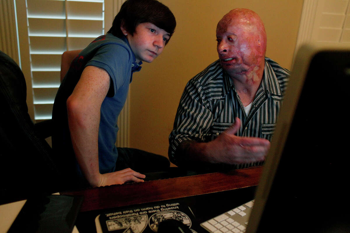 Bobby Henline, an Army veteran who was burned when his humvee was hit by a roadside bomb in Iraq, talks to his son, Skylar Henline, 14, about donating to the "Kony 2012" campaign after Skylar got his father to watch the video and asked him to pledge at their home in Universal City on Thursday, March 8, 2012. LISA KRANTZ/San Antonio Express-News