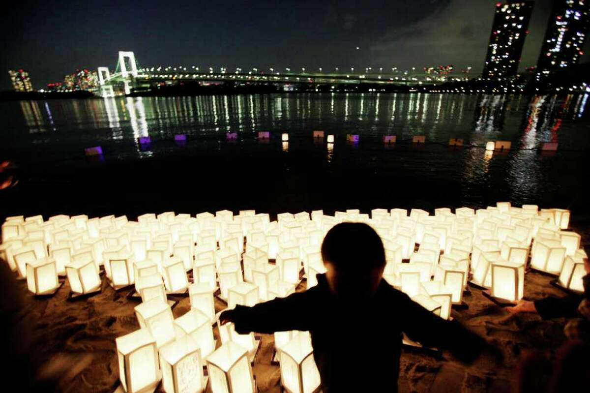A young boy walks past lanterns placed at the shore in Tokyo Bay to mark the first anniversary of the earthquake and tsunami which devastated northeastern Japan, in Tokyo. (AP Photo/Greg Baker)