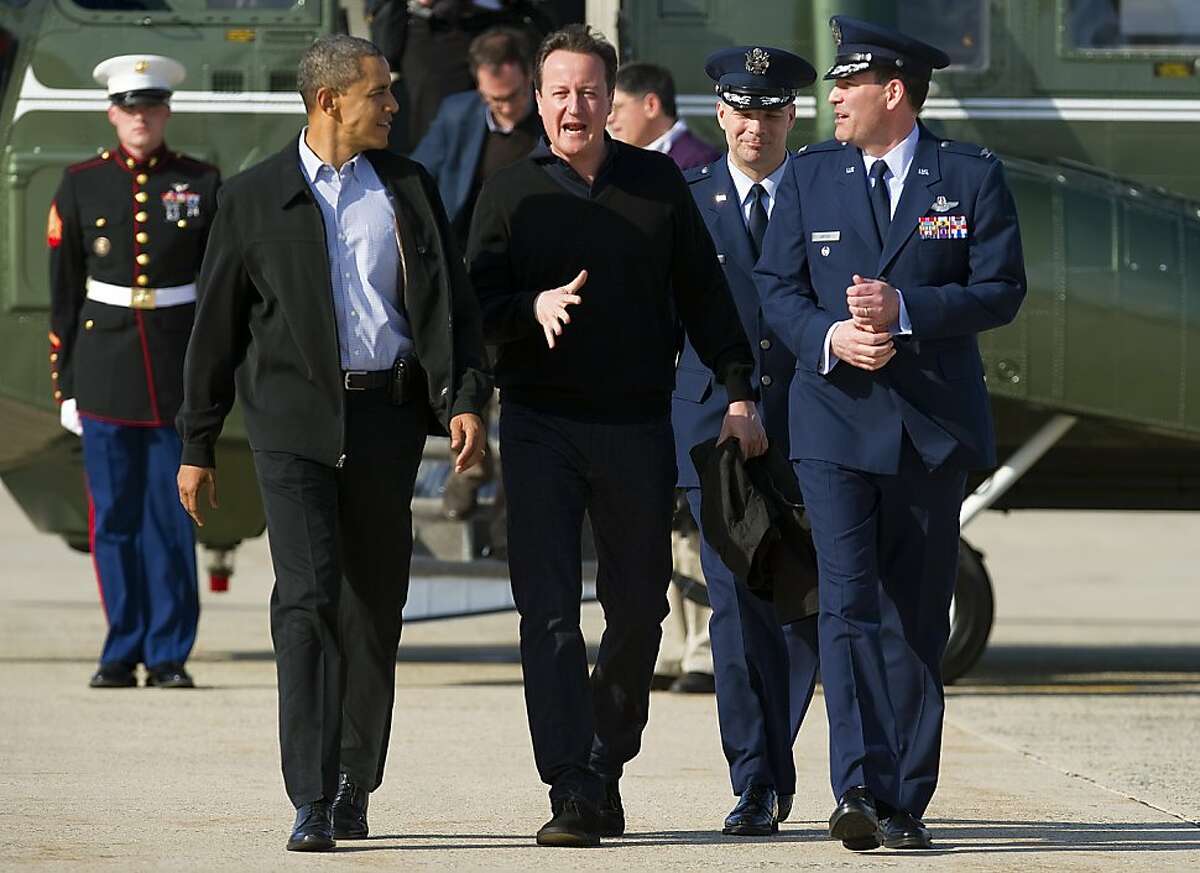US President Barack Obama (L) and British Prime Minister David Cameron (C) walk off Marine One March 13, 2012 at Joint Base Andrews, MD, to board Air Force One for a trip to Dayton Ohio to attend the NCAA Division I Men's Basketball Championship First Four at the University of Dayton.