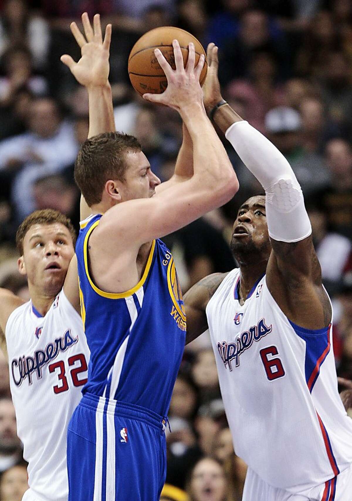 Golden State Warriors' David Lee, center, shoots between Los Angeles Clippers' Blake Griffin (32) and DeAndre Jordan (6) defend in the first half of an NBA basketball game, Sunday, March 11, 2012, in Los Angeles. (AP Photo/Jason Redmond)