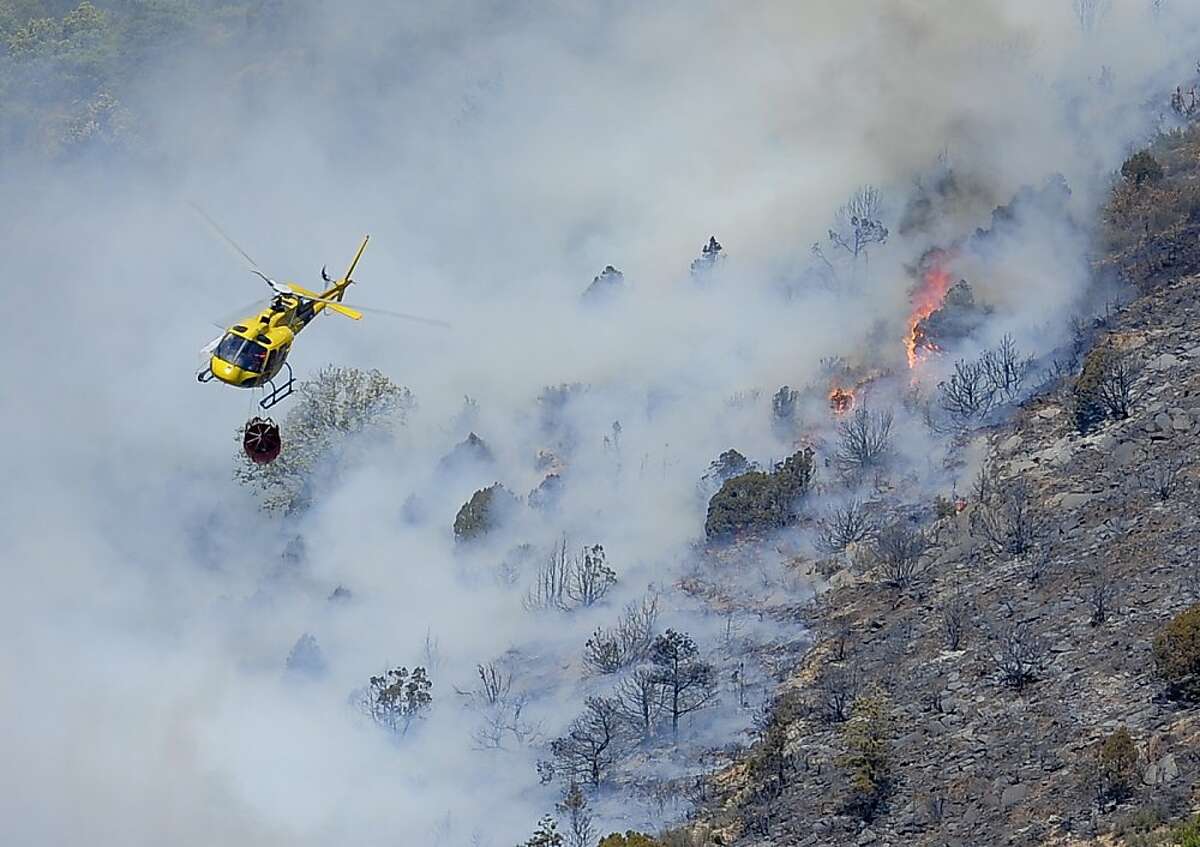 A helicopter drops water on one of the four wildfires that have so far ravaged 1,200 hectares (3,000 acres) of land, in the northeastern region of Catalonia, near the northern Spain village of Gerri de la Sal on March 9, 2012. Emergency services workers evacuated about 200 people from their homes on Thursday because of the risk from the flames but the majority have already been allowed to return to their homes. Spain is struggling through its driest winter since the 1940s, according to the national weather office. AFP PHOTO/ TOPSHOTS/ JOSEP LAGO (Photo credit should read JOSEP LAGO/AFP/Getty Images)