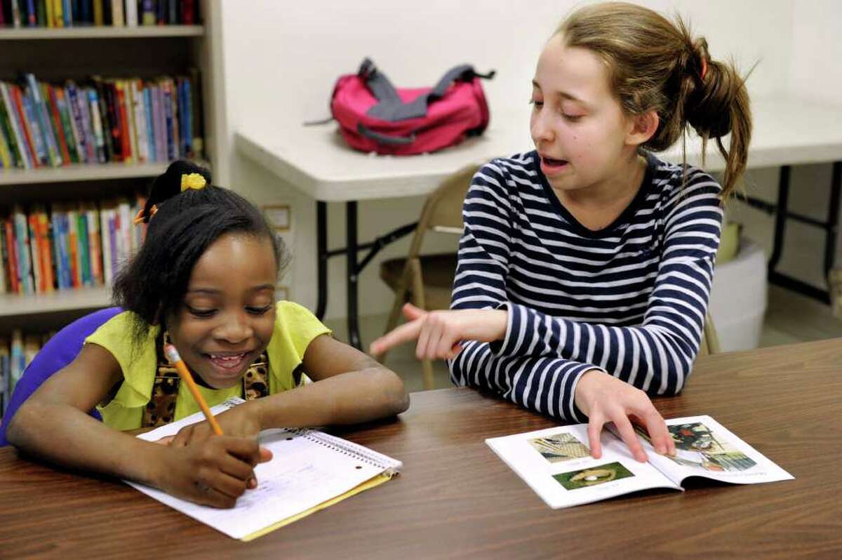 Jasmine Brown, 7, left, gets help with her homework from Ally Brown, 13, of Redding. Ally is with the Youth Volunteer Corps. The kids are spending time together in the H.O.P.E. Program at New Hope Baptist Church Monday, March 12, 2012.