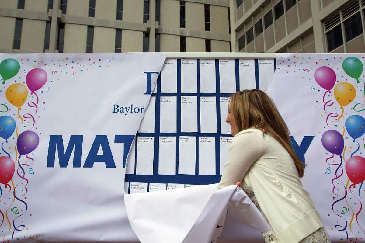 Class president Amy Pealrman tears the wrapping off a board covered in match result letters for fourth-year medical students during Match Day ceremonies at the Baylor College of Medicine.