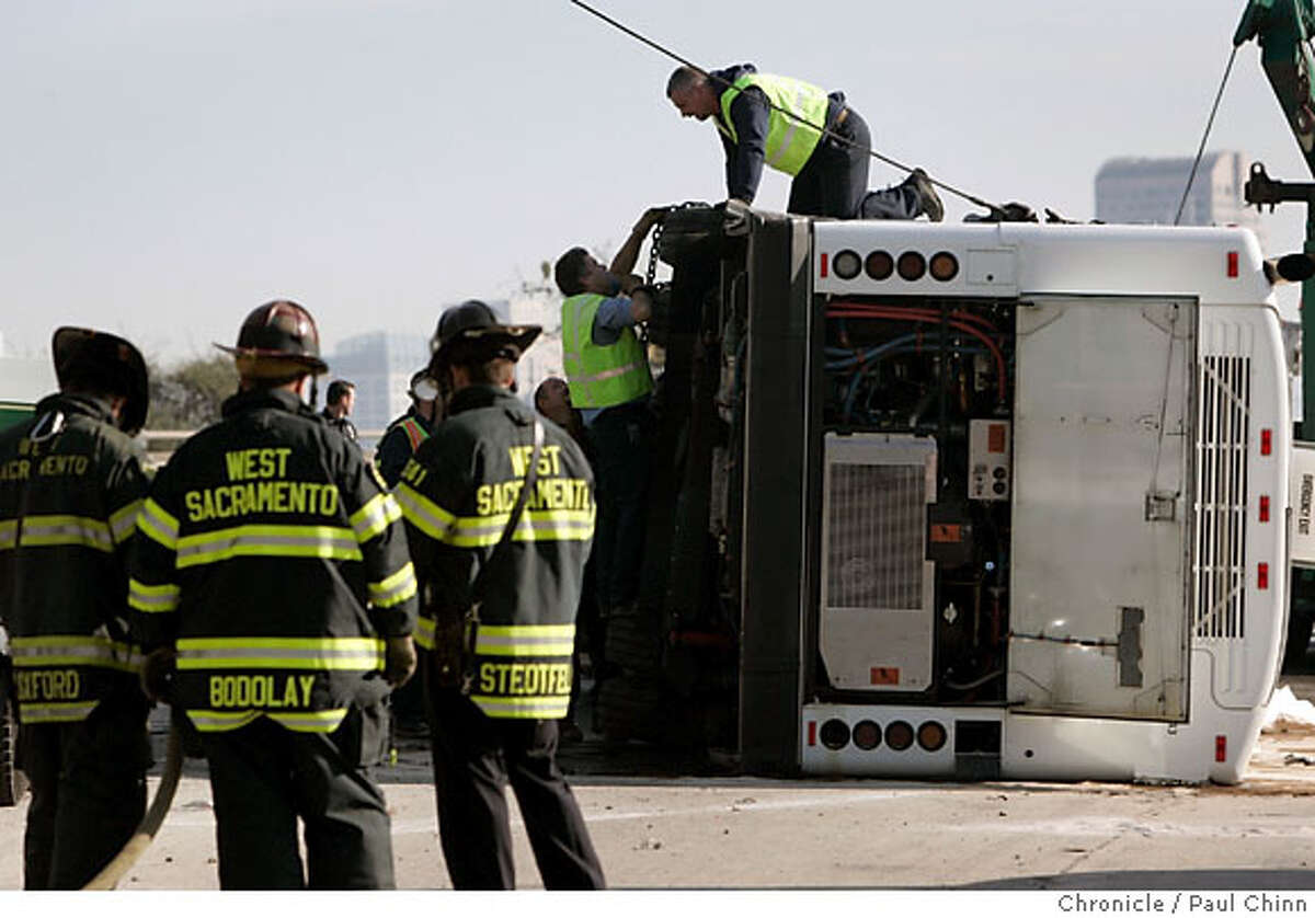 Firefighters stand watch as a tow truck crew prepares to upright a bus that crashed on Highway 50 at Jefferson Boulevard in West Sacramento, Calif. on Thursday, Nov. 30, 2006. More than 20 occupants were slightly injured when the bus overturned while shuttling students and faculty from the UC Davis campus to the university's medical center in Sacramento. Eastbound lanes were closed for several hours. PAUL CHINN/The Chronicle