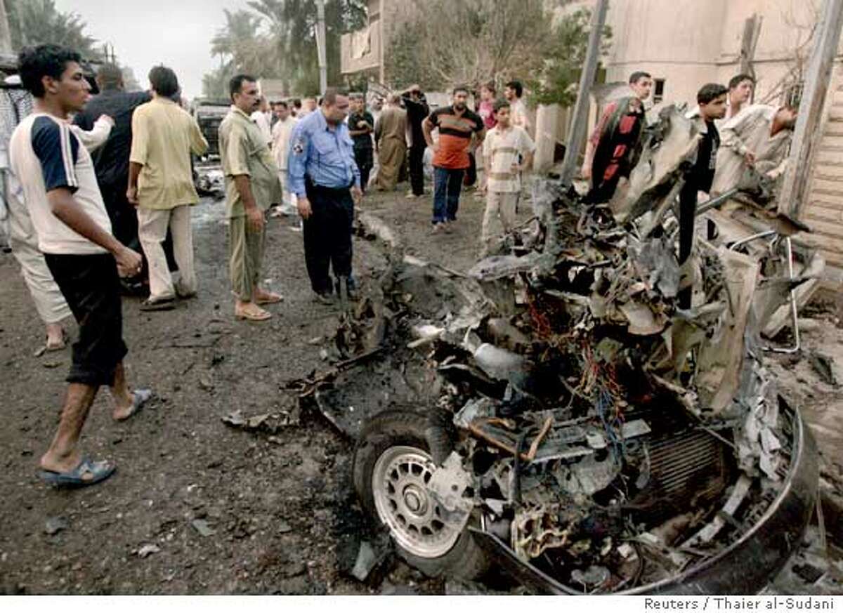 Residents and a policeman look at the wreckage of a vehicle used in a car bomb attack that targeted a Shi'ite wedding procession in Baghdad October 31, 2006. A car bomb ripped through a wedding procession in northeastern Baghdad on Tuesday, killing up to 10 people, an Interior Ministry source said. REUTERS/Thaier al-Sudani (IRAQ)