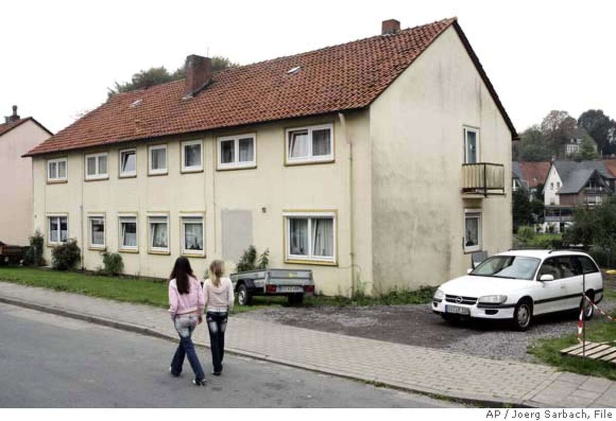 Two girls pass by the house where a 36-year-old man from Iraq, suspected of spreading messages by al-Qaida leaders on the Internet over the past year, was arrested in Osnabrueck, Germany, Tuesday, Oct. 10, 2006. He was accused of spreading audio and video messages by leaders of al-Qaida and al-Qaida in Iraq on the Internet from his home "in several cases since Sept. 24, 2005" _ and "in doing so of having supported these groups in their terrorist activities and aims." (AP Photo/Joerg Sarbach)