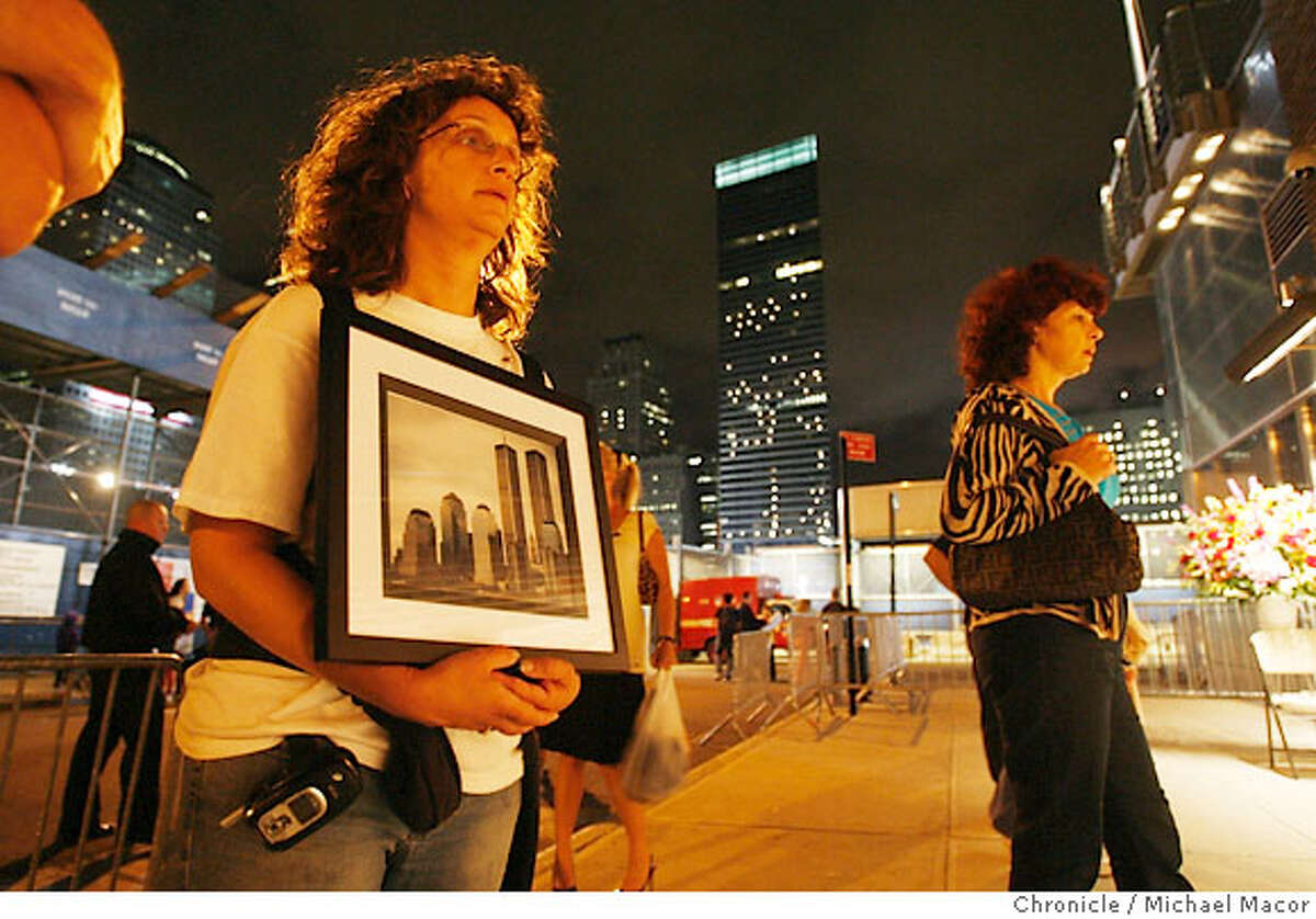 Tracy Armentano, clutching a photo of the Twin Towers, of Rocky Hill, Conn. makes the visit to Ground Zero for the fourth straight year. A block from the World Trade Center site. She looks over the memorial display at House 10-FDNY at the south edge of Ground Zero. The evening before the anniversary of 9/11, around the Ground Zero site. A visit to New York City as it prepares for the 5 year anniversary of the 9/11 attacks on the World Trade Center. Event in, New York, NY, on 9/10/06. Photo by: Michael Macor/ San Francisco Chronicle