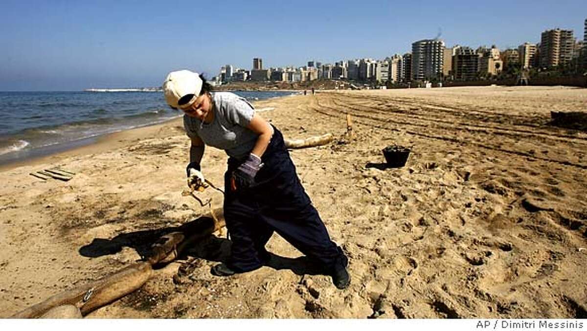A volunteer from Green Line NGO clean Ramlet-el-Baida beach in Beirut damaged by an oil spill caused by Israeli bombardment during the month-long war on Thursday Aug. 24, 2006. Some 110,000 barrels began pouring into the Mediterranean after Israeli warplanes on July 14 hit a coastal power plant at Jiyeh, 12 miles south of Beirut. More missiles hit a day later. Six fuel tanks ruptured in all, sparking explosions that knocked out a dike meant to prevent spills. (AP Photo/Dimitri Messinis)