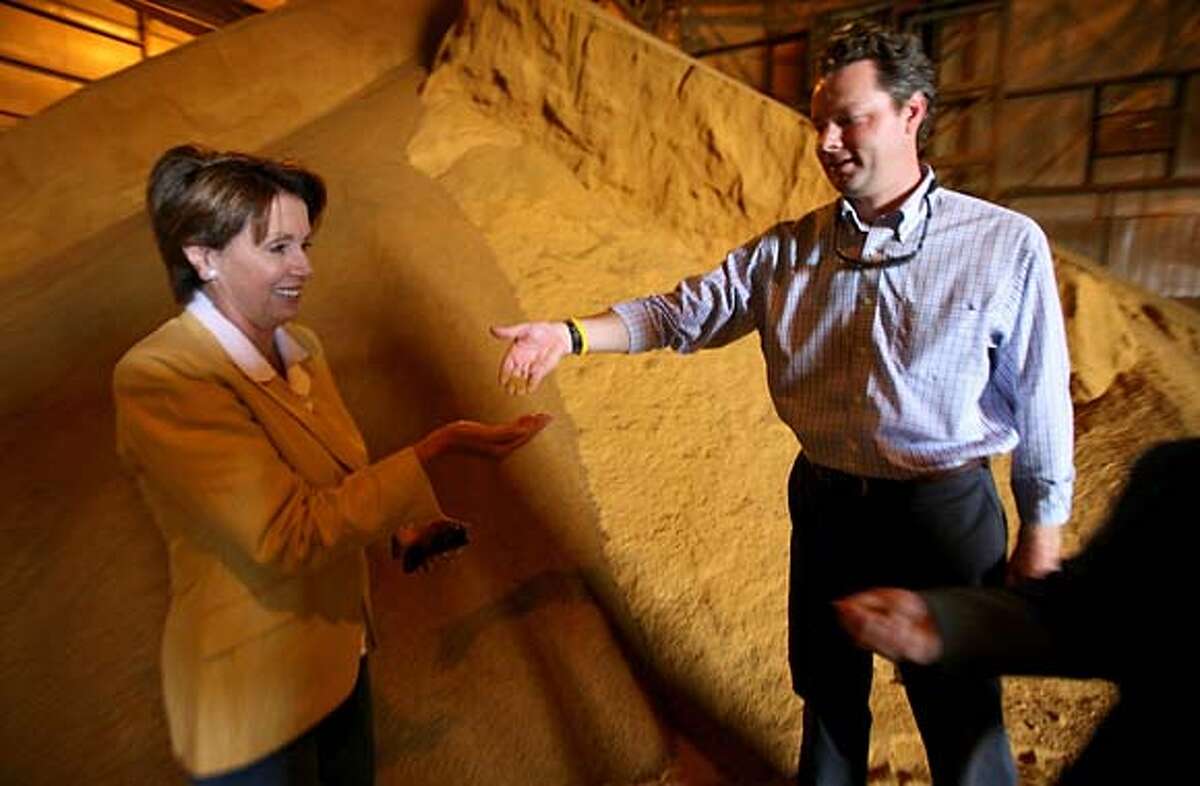 U.S. House of Representatives Democratic Leader Nancy Pelosi tours the Chippewa Valley Ethanol Plant and Fibrominn facility in Benson, MN. Wednesday, August 2, 2006. Minnesota State Sen Aaron Peterson hands dry distillers grain, an ethonal biproduct, to Pelosi.