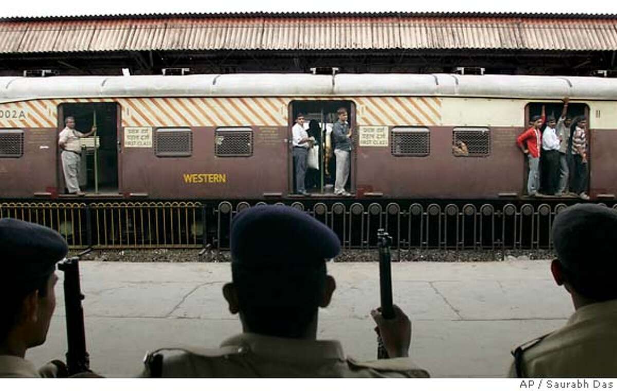 Police officers guard a nearly empty Mahim station during evening rush hour, as a train enters the station in Bombay, India, Wednesday July 12, 2006. Indian investigators on Wednesday combed through the twisted and torn wreckage of train cars ripped apart a day earlier by coordinated bombings that killed at least 200 people and wounded more than 700 during the city's evening rush hour. (AP Photo/ Saurabh Das)