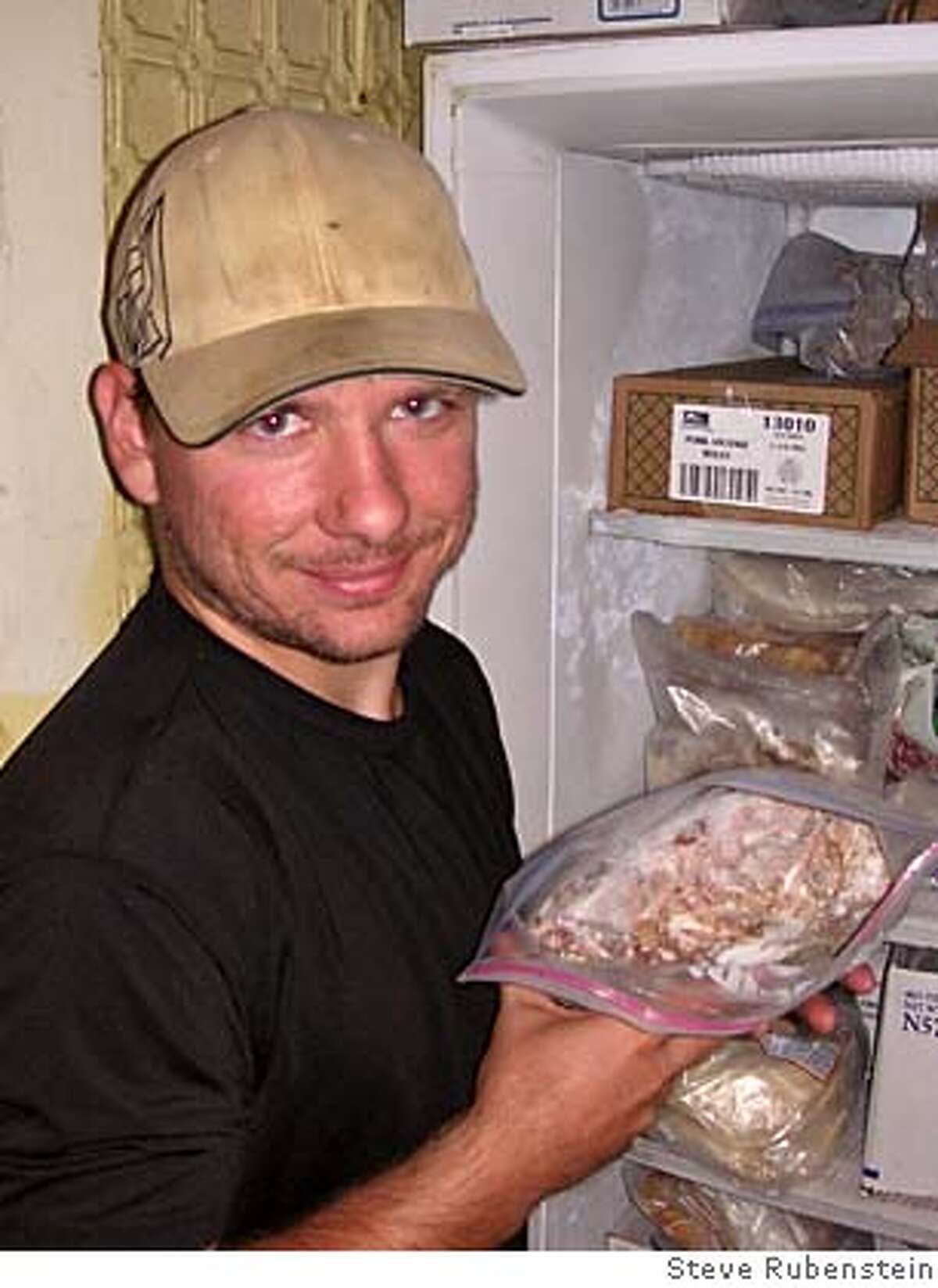 Holding a bag of frozen bull testicles in front of the freezer is Phil Fisher, bartender and testicle cook at the Ryegate Bar and Cafe in Ryegate MT, home of the annual, controversial testicle festival. Photo by Steve Rubenstein