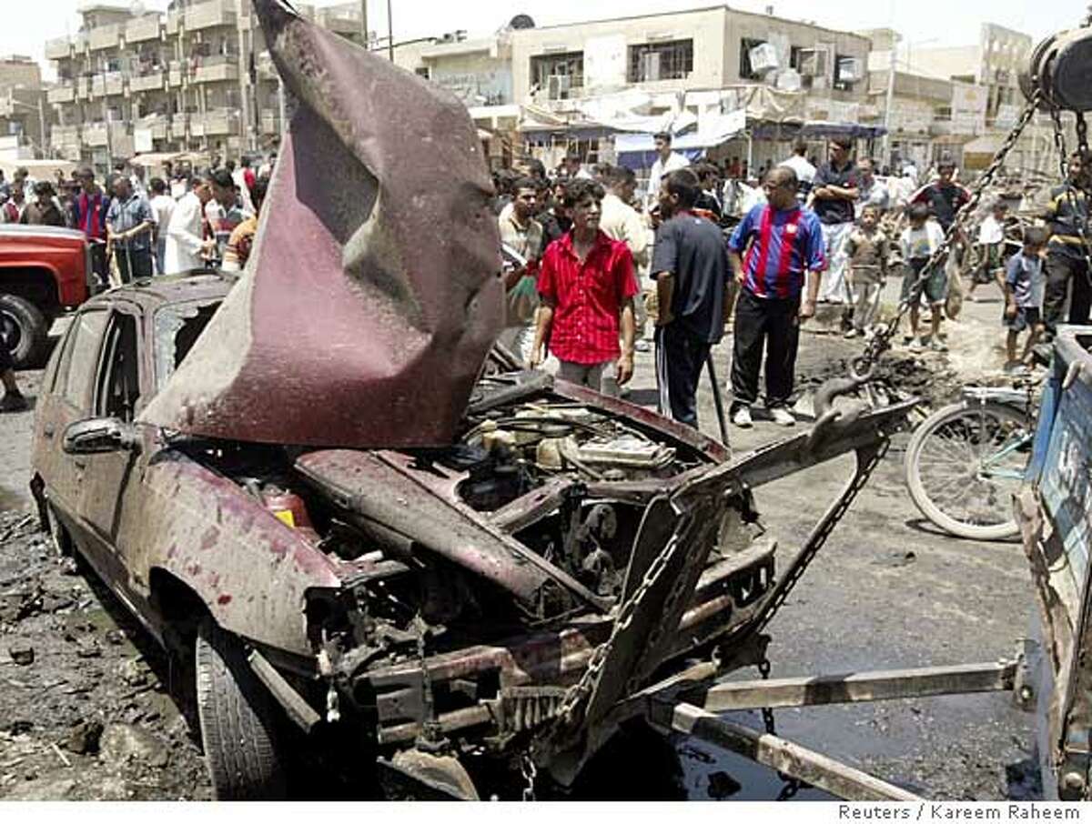 A damaged car is towed from the scene of a car bomb attack in a market in Baghdad's Sadr city