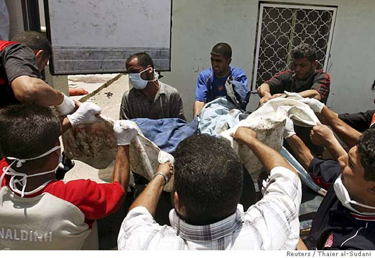Residents carry the body of a market car bomb attack victim into a refrigerated truck in Baghdad's Sadr city