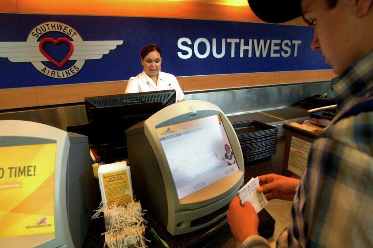 Southwest Airlines ticketing agent Amy Jackson, left, checks in customers at Hobby Airport.