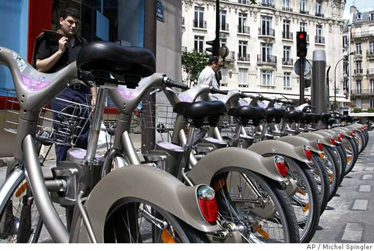 Men examine new bicycles known as "Velib" in Paris, Saturday, July 14, 2007. Starting July 15, more than 10,600 bikes will be posted all over town at 750 stations, and the numbers of both will nearly double by the year's end. The great news for tourists is that City Hall has made sure the service is convenient for tourists, not just Parisians, by offering short-term passes and access in eight languages. The idea is flexibility: You grab a bike from any station around town, they pop up every 330 yards or so, and park it at any other station. (AP Photo/Michel Spingler)