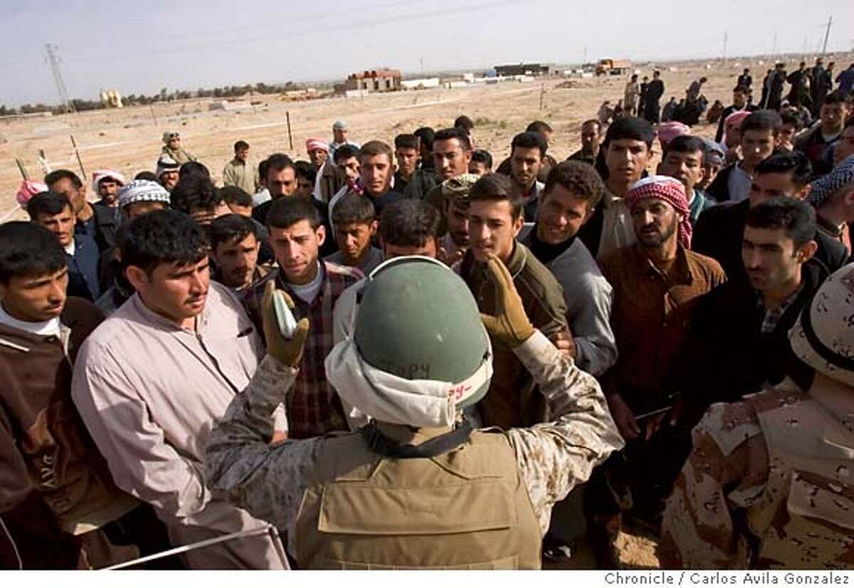 IRAQ26_184_CAG.CR2 An Iraqi army interpreter tries to calm the crowd of enlistees as they are confused about the screening process to join the Iraqi army. Many of the men are joining because it is a well-paying job, with salaries starting at around $400 per month. The 1st Battalion of the 7th Marine Regiment conducted an enrollment for new soldiers of the Iraqi Army on Friday, March 24, 2006, outside Al Qaim, Iraq, hoping to enlist 300 men into the fledgeling army. The men who were accepted, were immediately taken to Habaniya, Iraq for training. Photo by Carlos Avila Gonzalez / The San Francisco Chronicle Photo taken on 3/23/06 in Al Qaim, Al Anbar Province, IRAQ. MANDATORY CREDIT FOR PHOTOG AND SAN FRANCISCO CHRONICLE/ -MAGS OUT