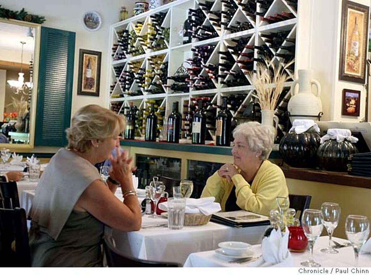 Two women enjoy lunch in front of a wall filled with wine at La Finestra Italian restaurant in Lafayette, Calif. on Wednesday, Sept. 12, 2007. PAUL CHINN/The Chronicle MANDATORY CREDIT FOR PHOTOGRAPHER AND S.F. CHRONICLE/NO SALES - MAGS OUT