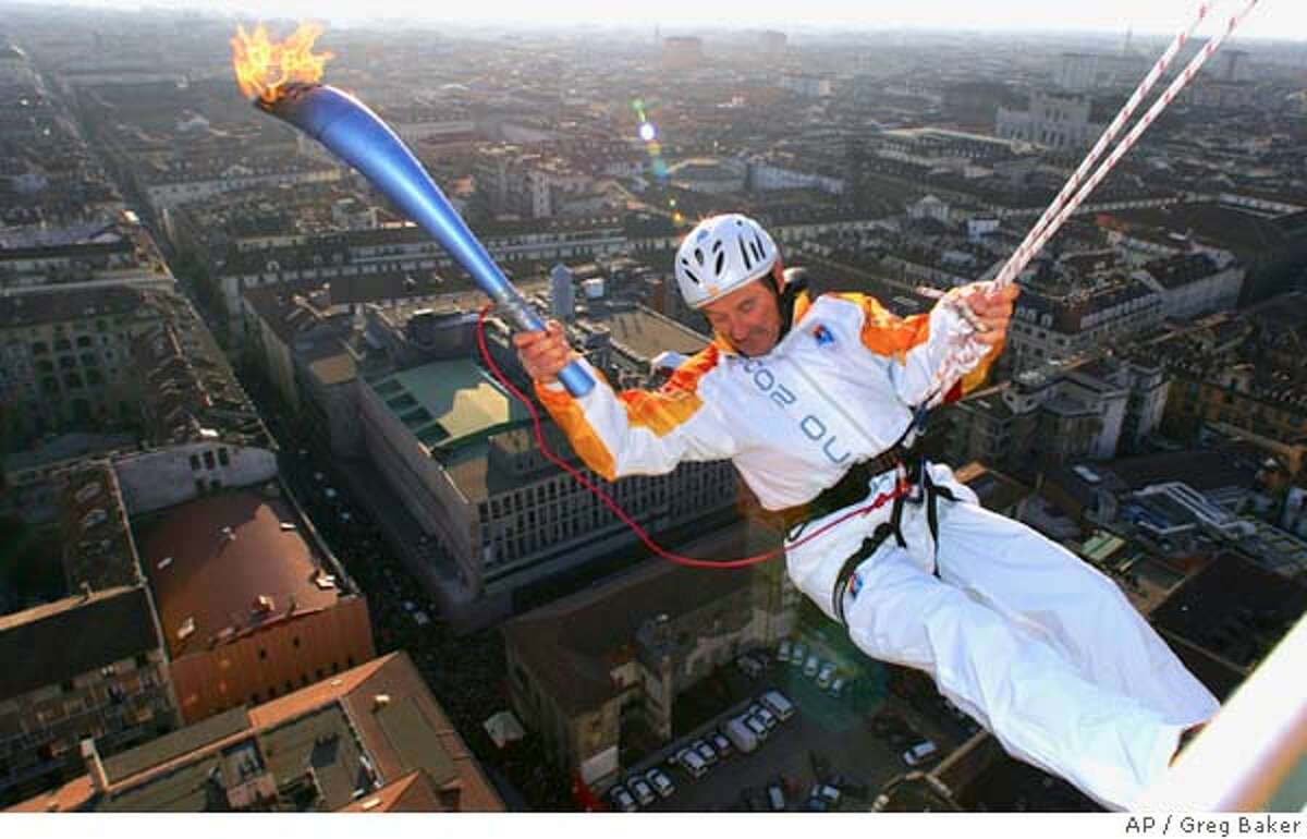 Alberto Re carries the Olympic flame as he hangs from the spire of Turin's Mole Antonelliana, the city's best known landmark, during the final leg of the torch relay for the Turin 2006 Winter Olympic Games, Friday, Feb. 10, 2006. Re is the director of a Mole Aotonelliana museum. (AP Photo/Greg Baker)Ran on: 02-11-2006 Fireworks erupt over the stadium after the Olympic flame is lit by fireworks during the Opening Ceremonies in Turin.