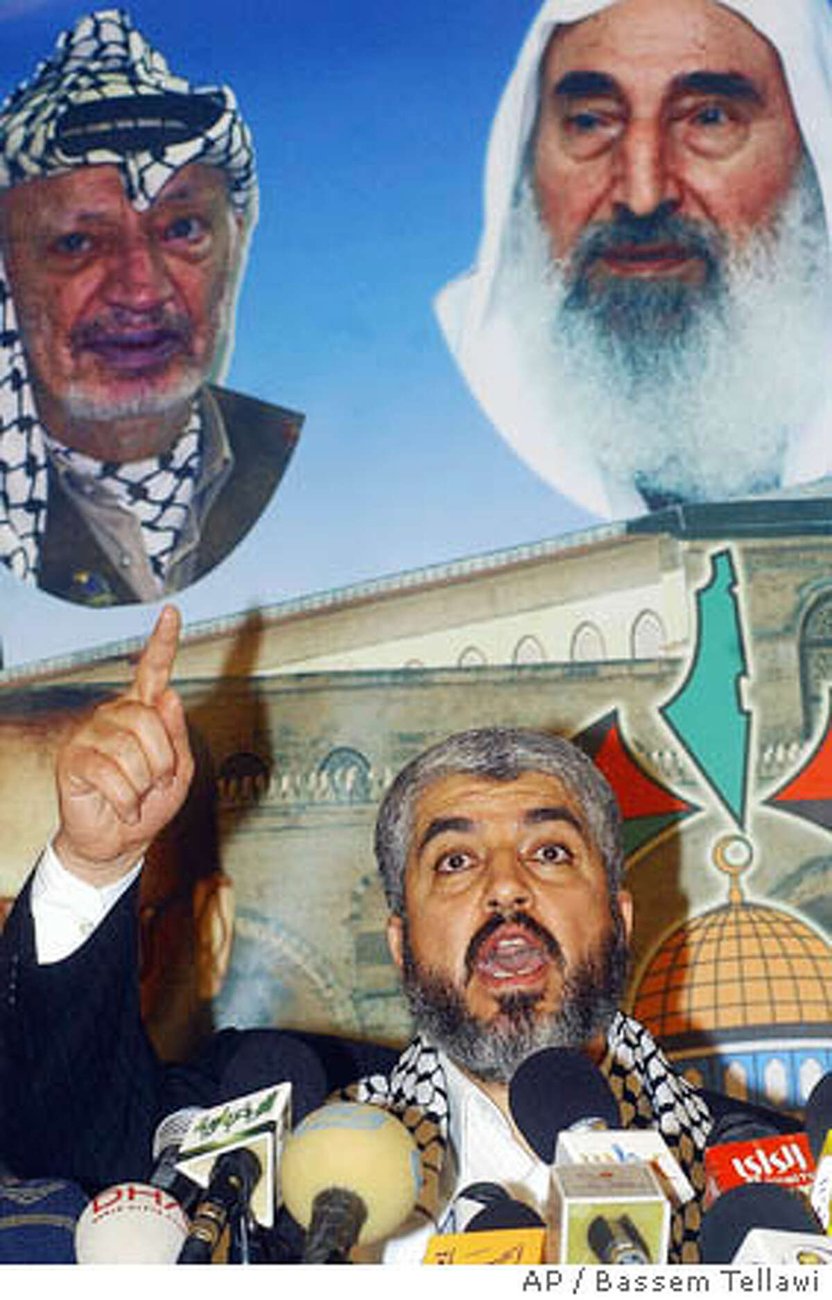 Hamas political leader Khaled Mashaal, whose group achieved a resounding victory in Palestinian elections this week, speaks at a news conference in Damascus, Syria Saturday, Jan. 28, 2006 saying that his group still wanted a partnership with other Palestinian factions and called for the world to respect the radical organization's landslide victory in parliamentary elections. Speaking to reporters from his base in Damascus, the Syrian capital, Khaled Mashaal outlined three goals: Reform of the Palestinian authority, sustaining its resistance to Israel and "arranging the Palestinian home." The Hamas chief also obliquely refused to disarm. Seen in poster in background, are images of the late PLO leader Yasser Arafat, and Sheik Ahmed Yassin, the quadriplegic spiritual force behind Hamas, who was killed in an Israeli air strike in Gaza in 2004. (AP Photo Bassem Tellawi)
